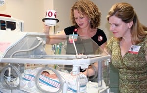 Shannon Lewis adjusts a NICU isolette web camera, whose more practical design and upgrade were led by Sarah Rhoads (right).  