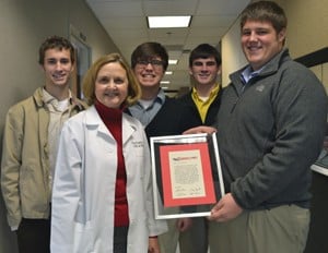 Adam Deacon, right, and his friends presented a check, a framed ultimate Frisbee tournament invitation and T-shirts with the tournament logo to UAMS’ Stacy Rudnicki, M.D., who directs the ALS program.