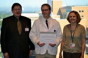 L. John Greenfield, M.D., left, and Stacy Rudnicki, M.D., right, present Kristoffer Nissinen with the AAN award. 