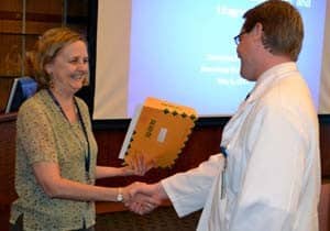 Stacy Rudnicki, M.D., presents Kristoffer Nissinen with his award during Neurology Grand Rounds May 6. 