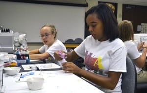 Zanna Collins of Wynne High School and Hannah Lawson (left) of Palestine High School make soap in the UAMS pharmacy lab.  