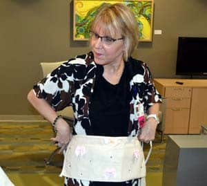 Maureen Smith, R.N., a registered nurse in the Breast Cancer Clinic, demonstrates one of the donated aprons.