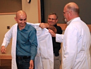 A doctoral candidate receives his lab coat during the Graduate School's Research Induction ceremony.