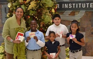 Students from the UALR Children International After-School Kids' Club, along with education manager Paula Rogers, display the coasters they made for patients.
