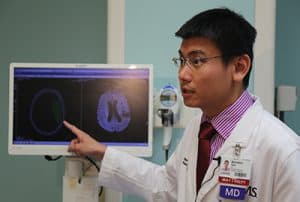 Benedict Tan, M.D., assistant professor in the UAMS College of Medicine Department of Neurology shows an image of Smith’s brain before and after her stroke treatment. 