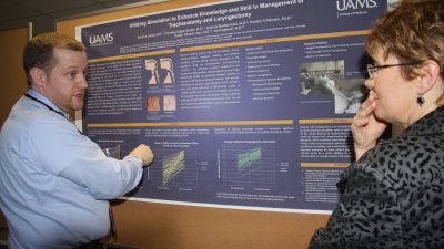 Physician explaining research in front of poster