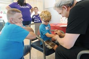 Noah Lahtinen, 5, gets his arm painted as his dad Brian watches during the NICU Reunion.