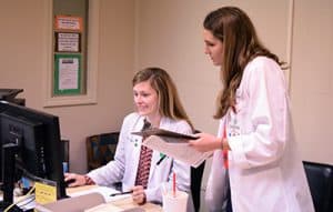 Kaitlin Long, a fourth-year pharmacy student, works with PA student Molly Koch to schedule a follow-up appointment for a patient at the 12th Street clinic.