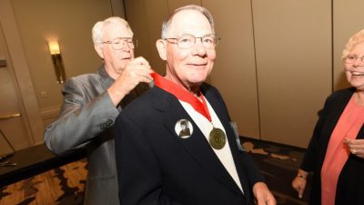 Dr. Carl Weber, COP '67 (center), has his Golden Graduate medallion draped by J.R. Ritchey.