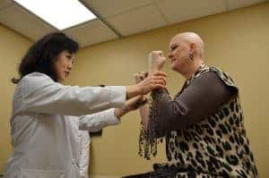Radiation oncologist Fen Xia, M.D., examines Tina Farber’s strength and coordination during a visit to the UAMS Radiation Oncology Center.