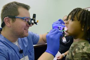 Joshua Farr, D.D.S., a resident in the General Practice Residency Program, coaxes a reluctant patient into letting Farr take a look at his teeth.
