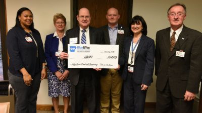 Patrick O'Sullivan (center), executive director of the Blue & You Foundation, presents an oversized check to UAMS Interim Chancellor Stephanie Gardner, Pharm.D., Ed.D.