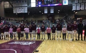 UAMS breast cancer survivors join the UALR men's basketball team on the court for the national anthem.