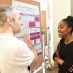 Student-professor pair talk near science poster