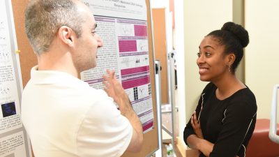 Student-professor pair talk near science poster
