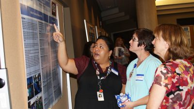 Maya Lopez, M.D., left, points to a research poster at an autism conference in Little Rock in 2016.