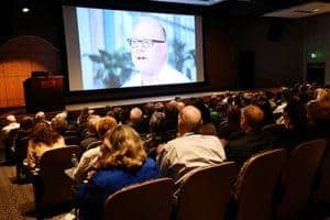 UAMS employees watch a video that highlights the success of the Level One Trauma Center and other programs at the start of the State of the University presentation.