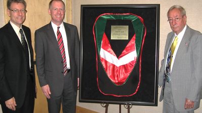 Fred Smith, right, stops for a photo with his sons, left, after receiving an honorary doctorate in 2011. The sash he received for the ceremony is framed and on display between them.