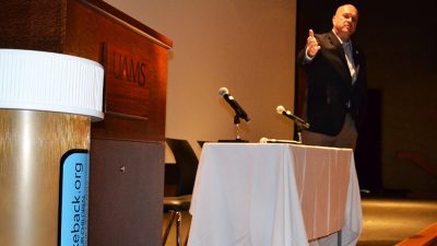 While speaking at the Pain Management Symposium, Kirk Lane points at a giant pill bottle he uses to promote the state's drug take-back program.