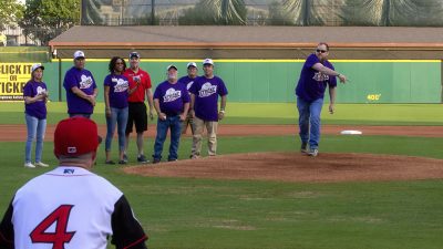 AR SAVES stroke survivor Dustin Martinez throws a symbolic strike against stroke as an Arkansas Travelers catcher waits to catch the ball at Strike Out Stroke Night at Dickey-Stephens Park.