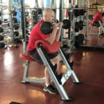 Adam Carter demonstrates how to use the center’s new Hoist preacher curl in the weight room.