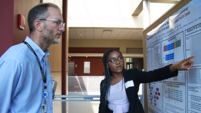 Student showing poster to professor