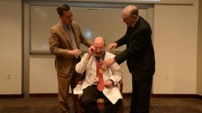 Seth Berney, M.D., receives his commemorative medallion from Chancellor Cam Patterson, M.D., MBA, and College of Medicine Dean Christopher T. Westfall, M.D.