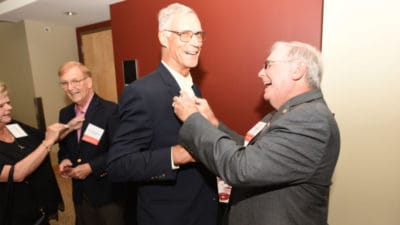 Jack Blackshear Jr., M.D., COM '68 (at right), pins a button on George Fielder Jr., M.D., COM '68 at the Friday night welcome reception.