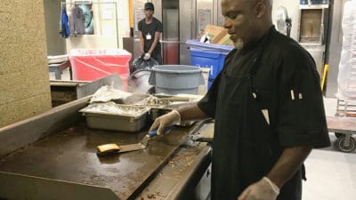 Wendell Foster, a Nutrition Services chef who prepares meals for patients, cooks a hamburger. On Oct. 2, patients will be able to order room service.