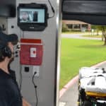 Sanjeeva Onteddu, M.D., center on the video monitor, works with ProMed Ambulance Service paramedics to demonstrate how the live video telemedicine system installed in the ambulance will work in the field.