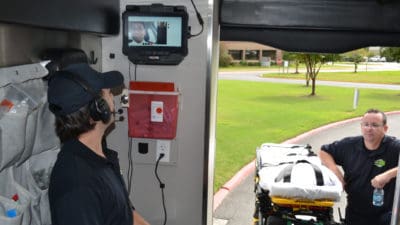 Sanjeeva Onteddu, M.D., center on the video monitor, works with ProMed Ambulance Service paramedics to demonstrate how the live video telemedicine system installed in the ambulance will work in the field.