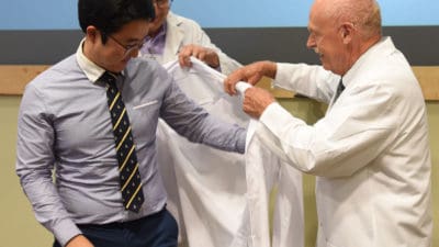 Student helped into white coat