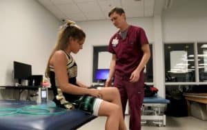 Nick Hargett, D.P.T. works with patient Addison Mann in physical therapy session using blood flow restriction therapy. 