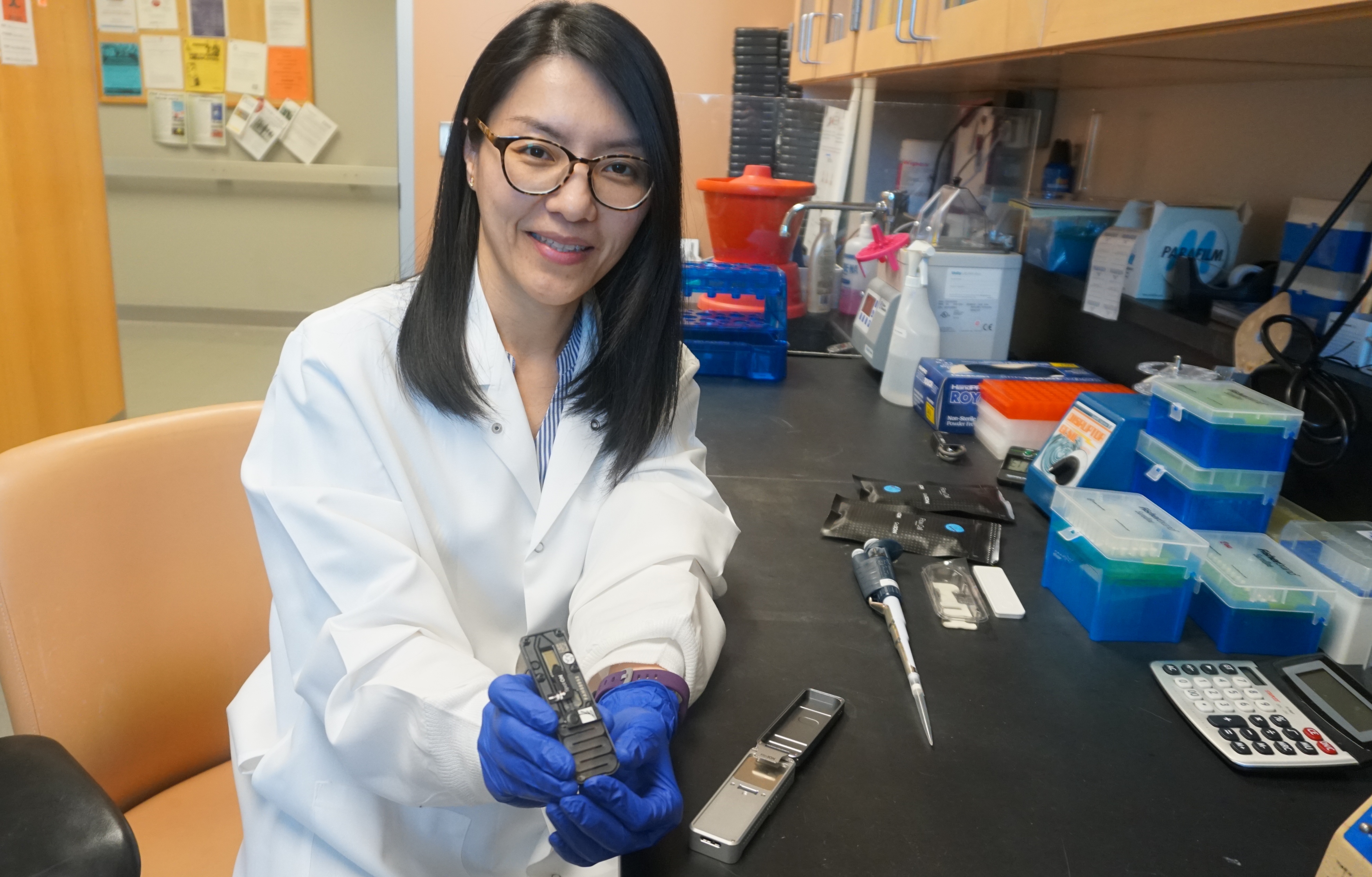 Thidathip (Tip) Wongsurawat, Ph.D., with the hand-held nanopore device used for the first time to sequence multiple viruses.