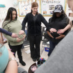 Pregnant women in circle touching bellies