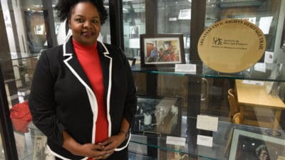 April Hughes standing next to her favorite elements in the exhibit, including a photo taken with Edith Irby Jones and a photo of Jones meeting Martin Luther King, Jr.