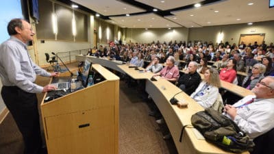 Scientist at podium addressing large crowd