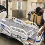 Jalen Morris (left) and Bradon Berry, contract employees with Stryker, assemble new patient beds in the UAMS loading dock. More than 300 patient received new beds in April.