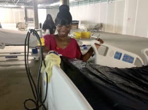 Marcia McKenzie cleans a new bed before it is outfitted with clean linens and covered in plastic for the move to a patient room.