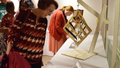 An Art from the Heart attendee examines Octahedral with Curve, a woodwork piece created by Shalese Fitzgerald.