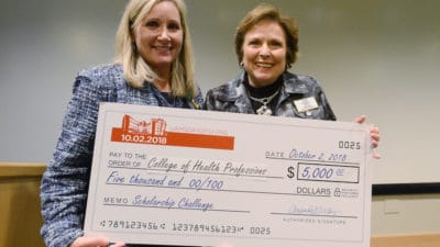 College of Health Professions Dean Susan Long, Ed.D., (left) accepts a check from Judy Sims, the then-chair of the college's Advisory Board, during a scholarship program in November.
