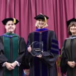 UAMS Chancellor Cam Patterson, M.D., MBA, and Provost Stephanie Gardner, Pharm.D, Ed.D., present Kristie Hadden, Ph.D., (center) with the Chancellor’s Award for Society and Health Education Excellence.