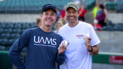 UAMS Chancellor, Cam Patterson, M.D., MBA, left, and stroke survivor Timothy Raines take a moment to display their baseballs before heading to the pitcher's mound.
