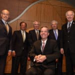 Patterson sits in his chair at the investiture ceremony. Behind him are (from left to right): Donald Bobbitt, Ph.D., Michael E. Mendelsohn, M.D., Steve Carpenter, M.D., John Goodson, and Gov. Asa Hutchinson.