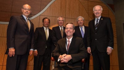 Patterson sits in his chair at the investiture ceremony. Behind him are (from left to right): Donald Bobbitt, Ph.D., Michael E. Mendelsohn, M.D., Steve Carpenter, M.D., John Goodson, and Gov. Asa Hutchinson.