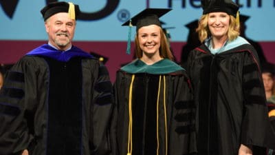 Kayla Copeland (center) is all smiles after receiving her academic hood from John Jefferson, Ph.D., chair of the Department of Physical Therapy, and Angel Holland, Ed.D., assistant professor. Copeland said she got a little teary when she saw her name -- Dr. Kayla Copeland -- on a sign.