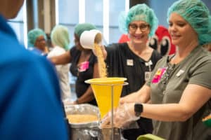 Members of Team UAMS pour ingredients into the funnel to make the meal kits. Participants made more than 36,000 meals at the Feed the Funnel event. <i>Photo credit, Bryan Clifton</i>