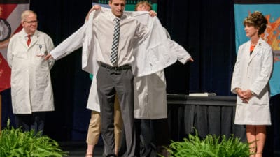 Student putting on white coat