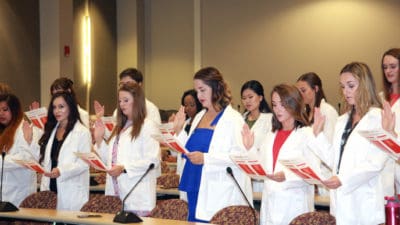 First-year students in the Department of Audiology and Speech Pathology in the College of Health Professions recite the Therapist's Oath during a white coat ceremony Aug. 16.