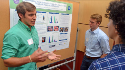 Two male students presenting research at poster